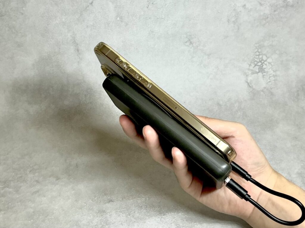 3coinsのモバイルバッテリーをスマホと重ねて手で持つ